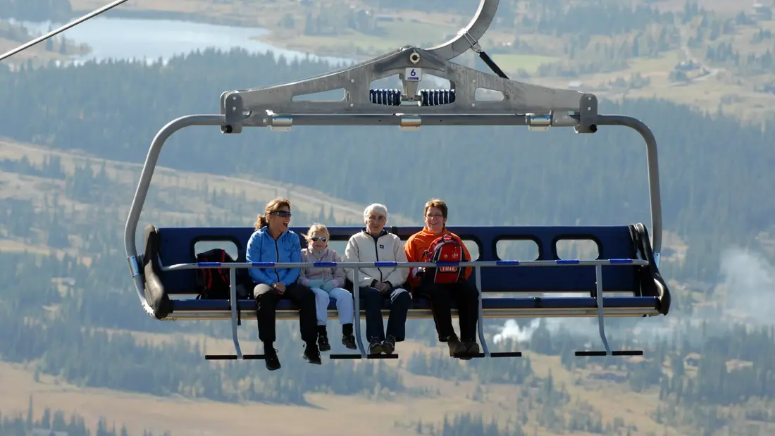 Personer sitter i skiheisen på sommerstid med utsikt over Skeikampen