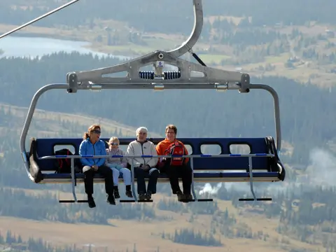 Personer sitter i skiheisen på sommerstid med utsikt over Skeikampen