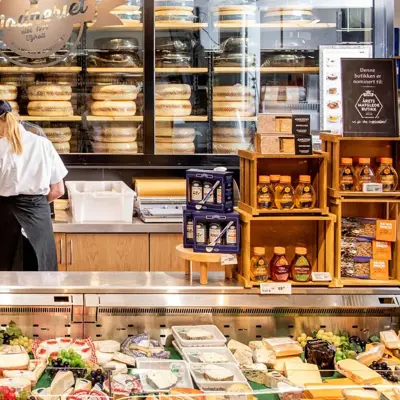 Dame som jobber bak en disk med diverse ost