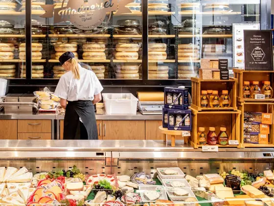 Dame som jobber bak en disk med diverse ost