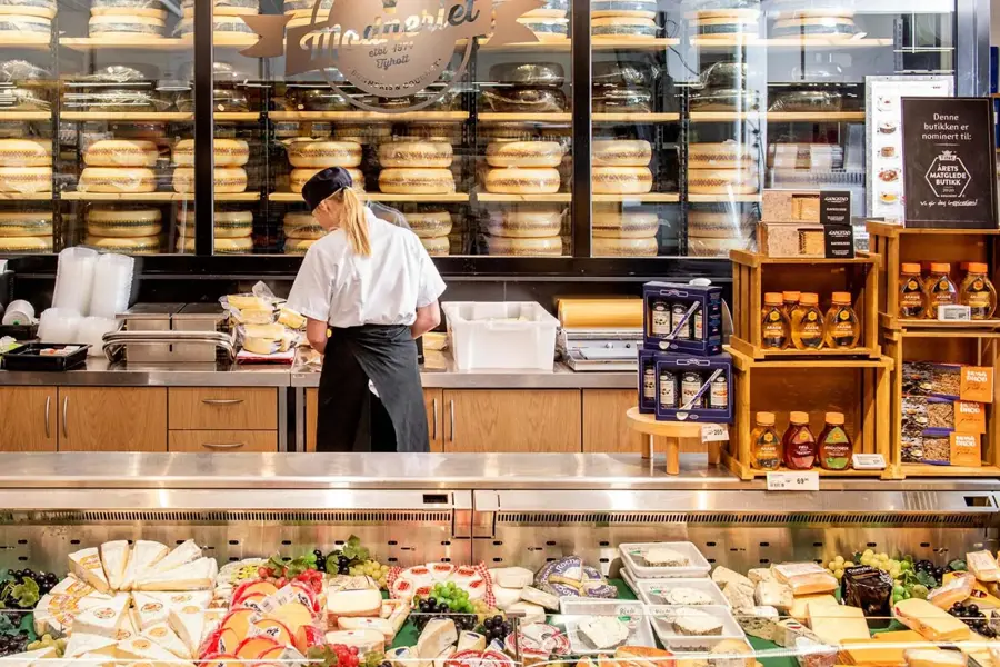 Dame som jobber bak en disk med diverse ost