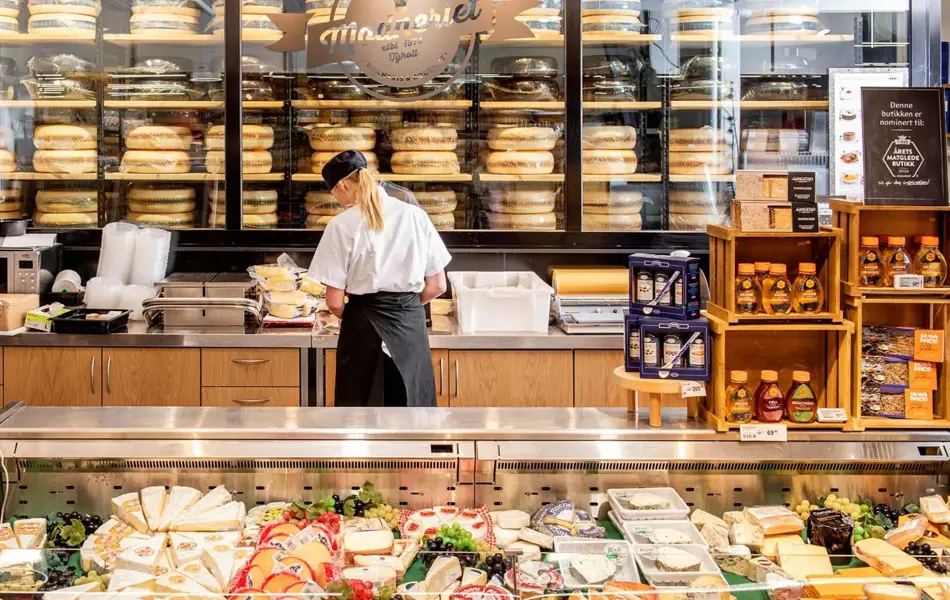 Dame som jobber bak en disk med diverse ost