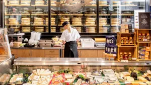 Dame som jobber bak en disk med diverse ost