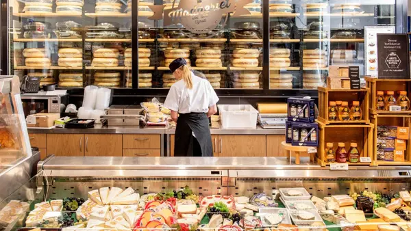 Dame som jobber bak en disk med diverse ost