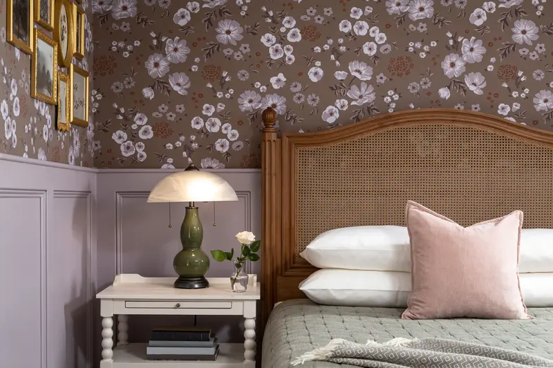 Soverom med seng i mørkt tre, vintage grønn lampe og blomstertapet på veggen 