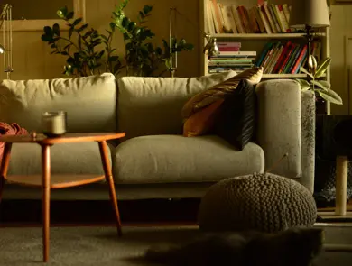 Stue med lun atmosfære og sofa med puter i høstlige farger og trebord med stearinlys i front