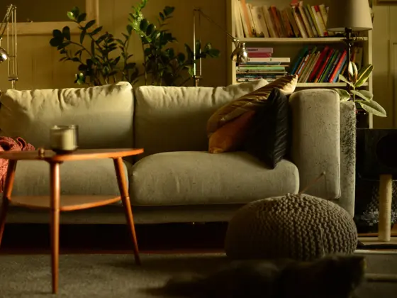 Stue med lun atmosfære og sofa med puter i høstlige farger og trebord med stearinlys i front