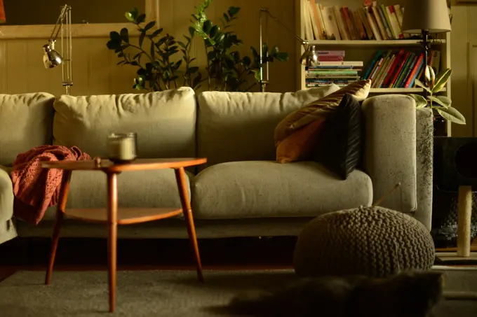 Stue med lun atmosfære og sofa med puter i høstlige farger og trebord med stearinlys i front