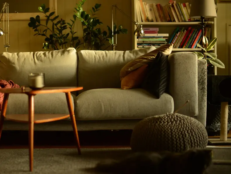 Stue med lun atmosfære og sofa med puter i høstlige farger og trebord med stearinlys i front