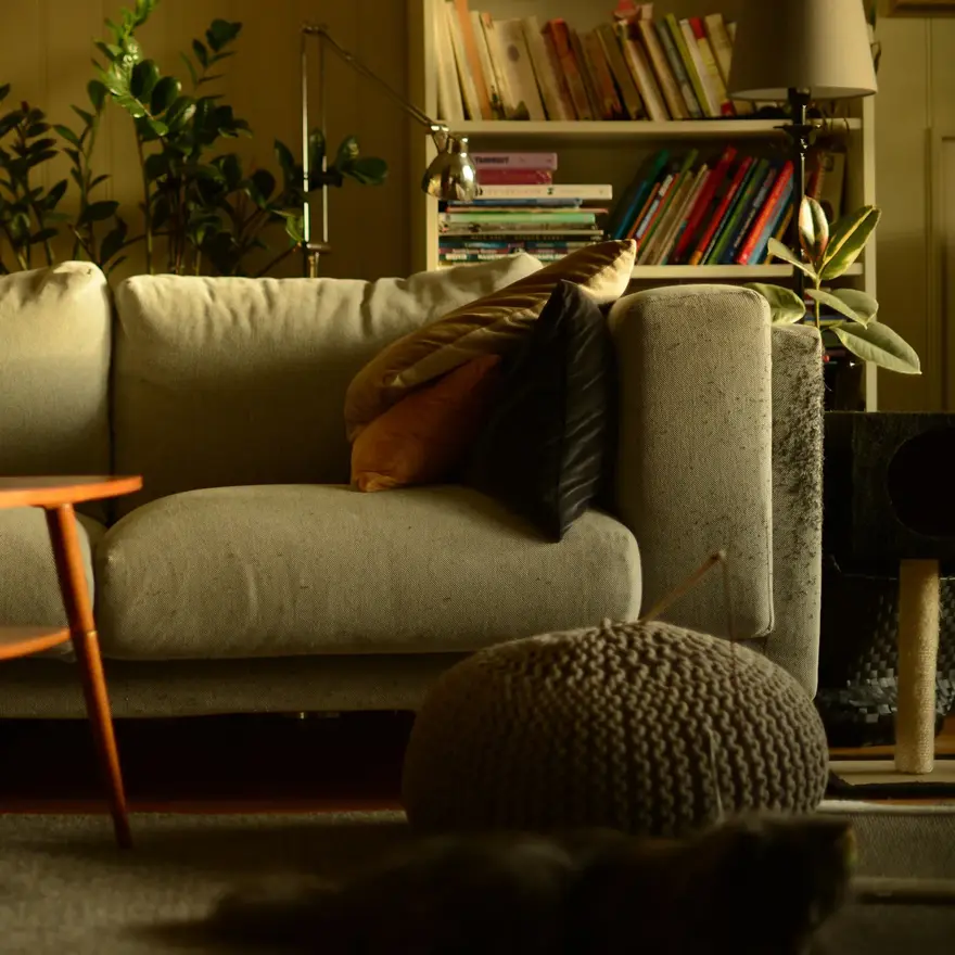 Stue med lun atmosfære og sofa med puter i høstlige farger og trebord med stearinlys i front