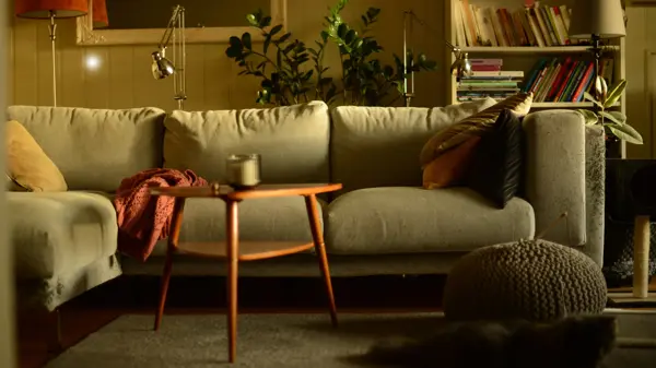 Stue med lun atmosfære og sofa med puter i høstlige farger og trebord med stearinlys i front