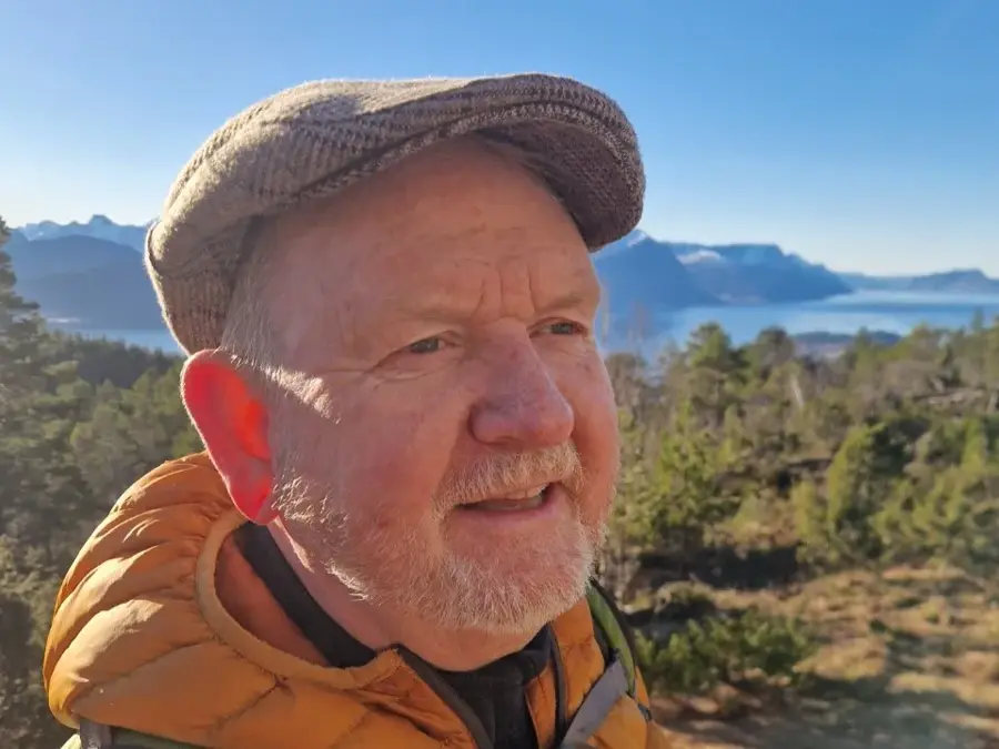 Mann med fjord og fjell i bakgrunnen