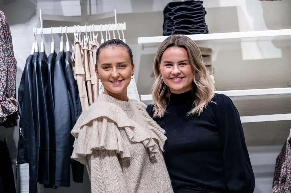 To smilende damer i butikk 