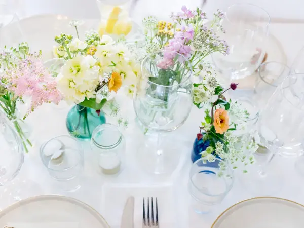 Hvitdekket bord dekorert med markblomster i små vaser
