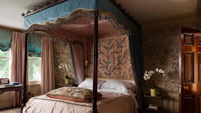 Rosa soverom med mønstret tapet og overdådig sengehimling