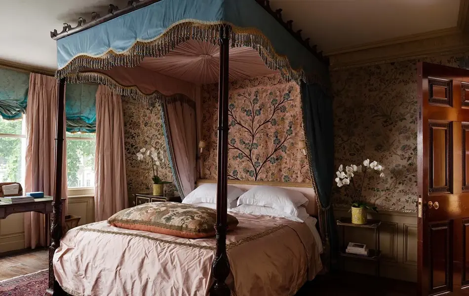 Rosa soverom med mønstret tapet og overdådig sengehimling