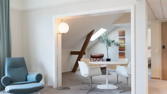 Oppholdsrom på suite med spisebord, stoler, og en blå lenestol