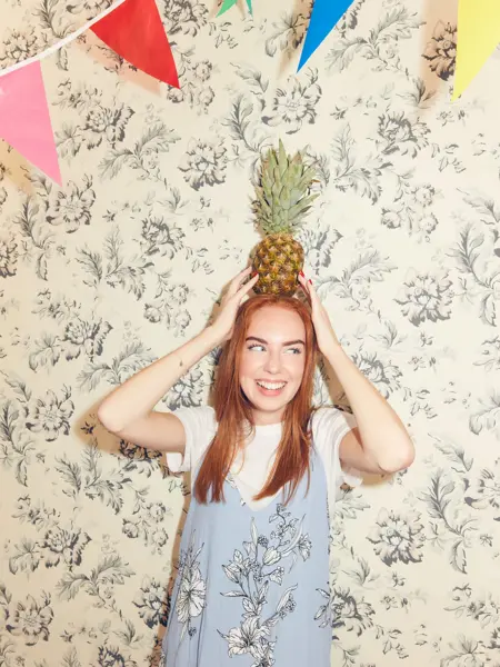 Jente som balanserer en ananas på hodet