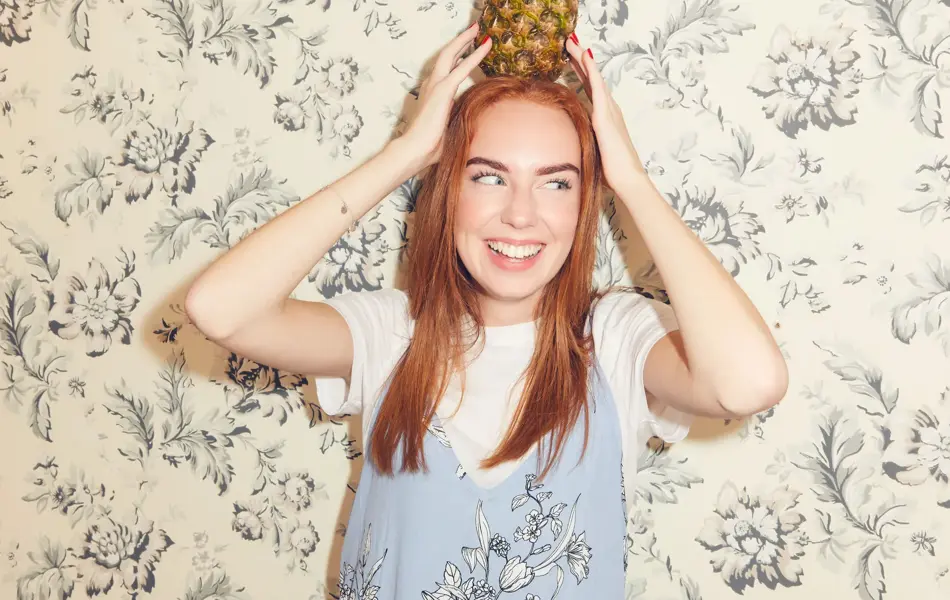 Jente som balanserer en ananas på hodet