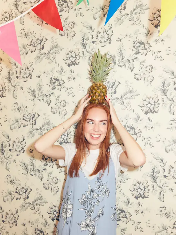Jente som balanserer en ananas på hodet