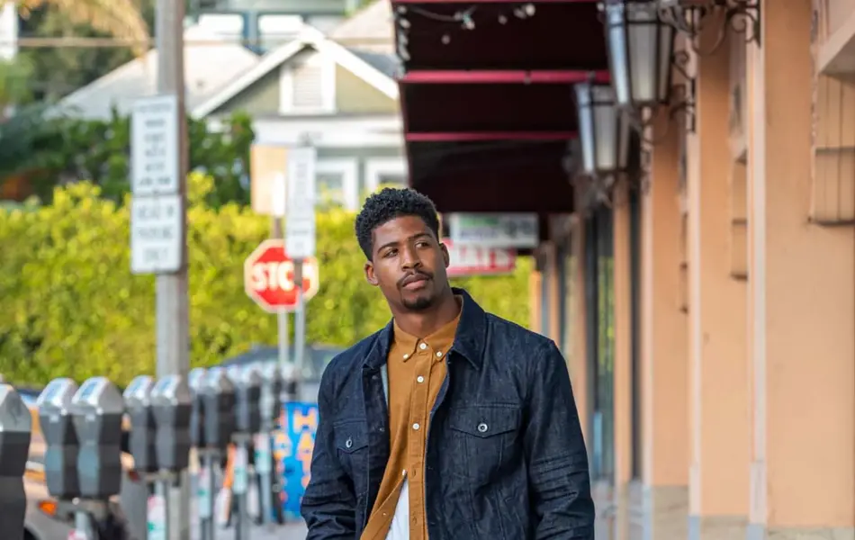 mann med grønn cargobukse, sennepsgul skjorte og mørk denim jakke