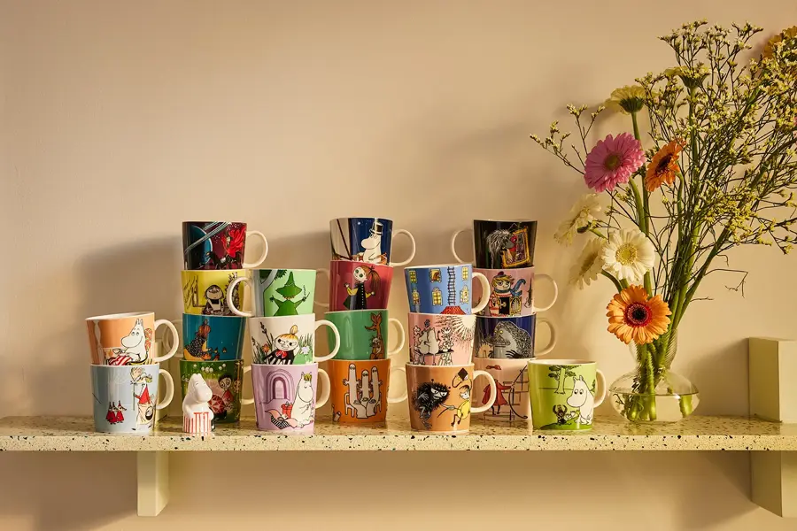 Mange kopper med mummitroll motiv på en hylle