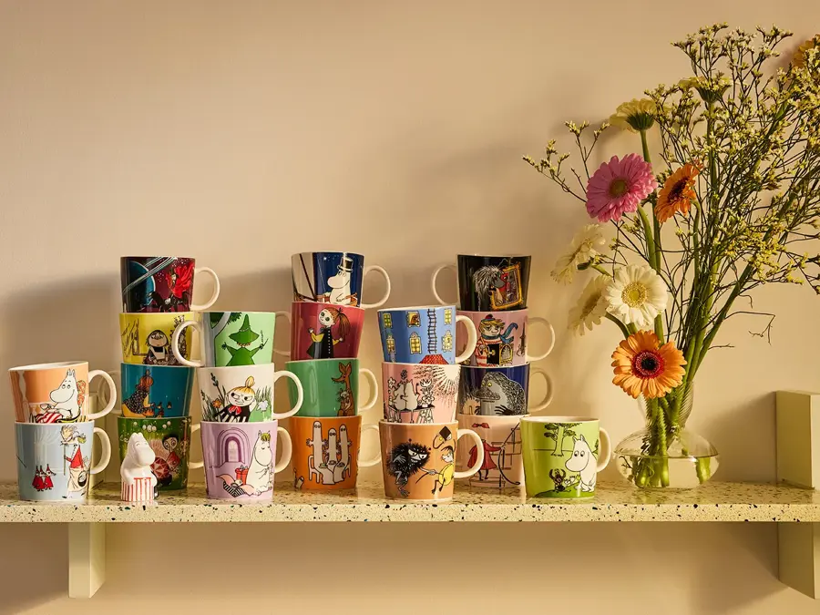 Mange kopper med mummitroll motiv på en hylle