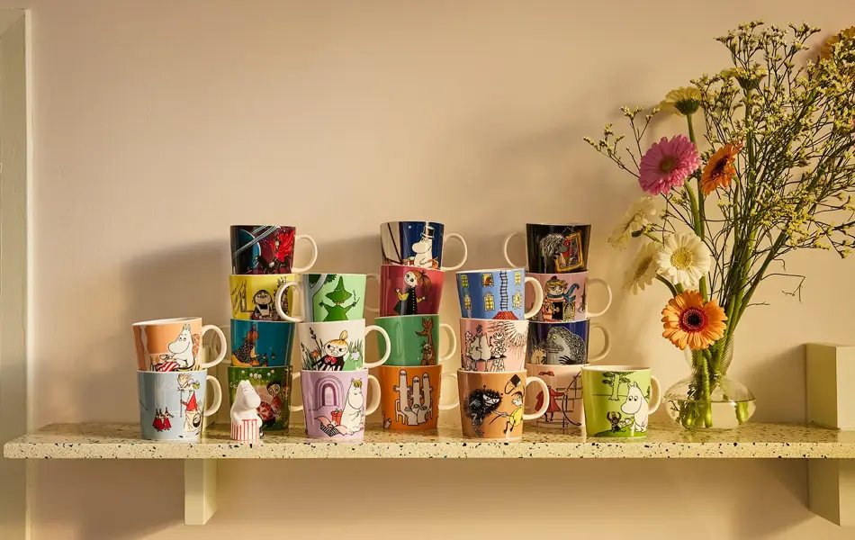 Mange kopper med mummitroll motiv på en hylle