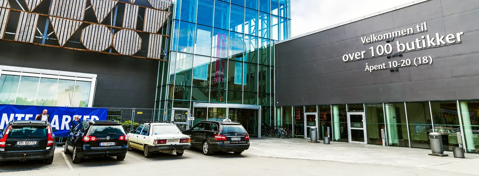 Fasadebilde av AMFI Steinkjer som viser biler parkert ved senterets inngang