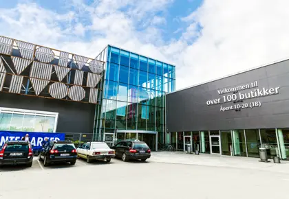 Fasadebilde av AMFI Steinkjer som viser biler parkert ved senterets inngang