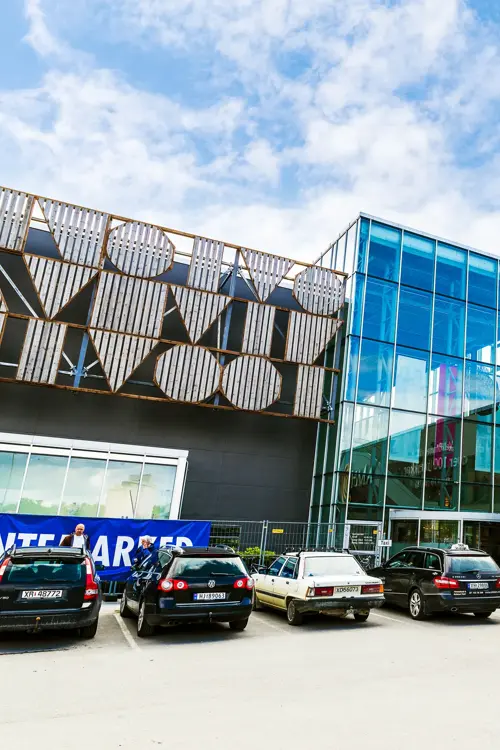 Fasadebilde av AMFI Steinkjer som viser biler parkert ved senterets inngang