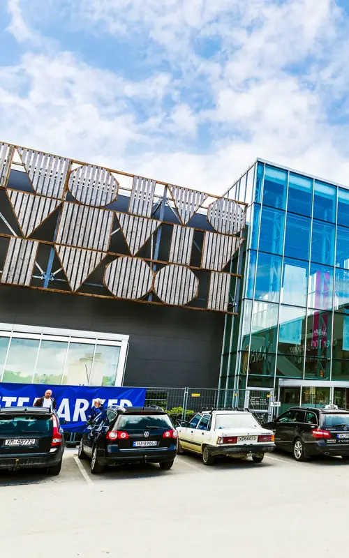 Fasadebilde av AMFI Steinkjer som viser biler parkert ved senterets inngang