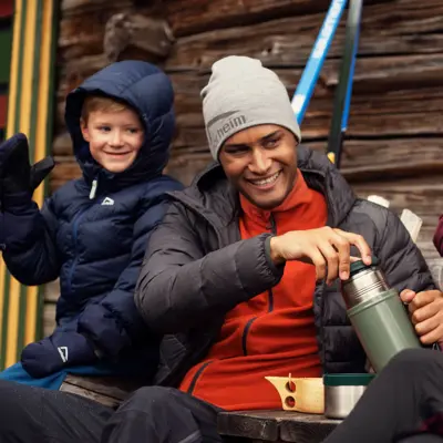 Friluftsfamilie med tre barn og to voksne smiler i uteklær