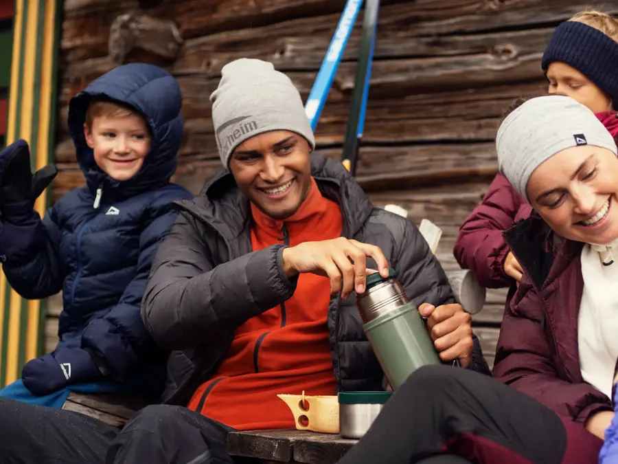 Friluftsfamilie med tre barn og to voksne smiler i uteklær