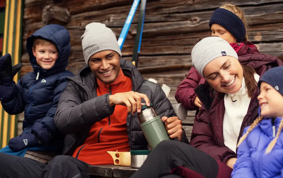 Friluftsfamilie med tre barn og to voksne smiler i uteklær