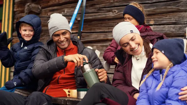 Friluftsfamilie med tre barn og to voksne smiler i uteklær