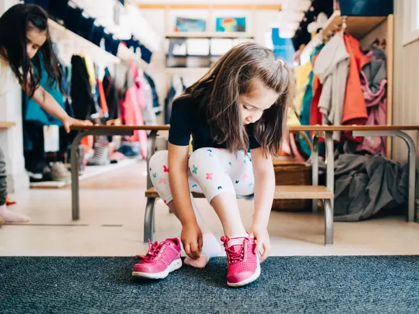 jente som tar på seg sko på skolen