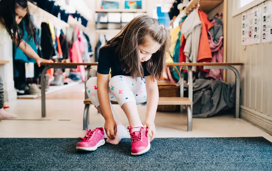 jente som tar på seg sko på skolen