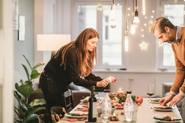 En mann og en dame dekker bordet til julefest