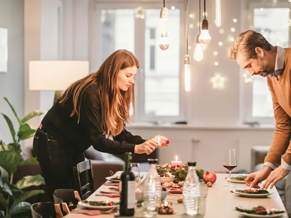 En mann og en dame dekker bordet til julefest