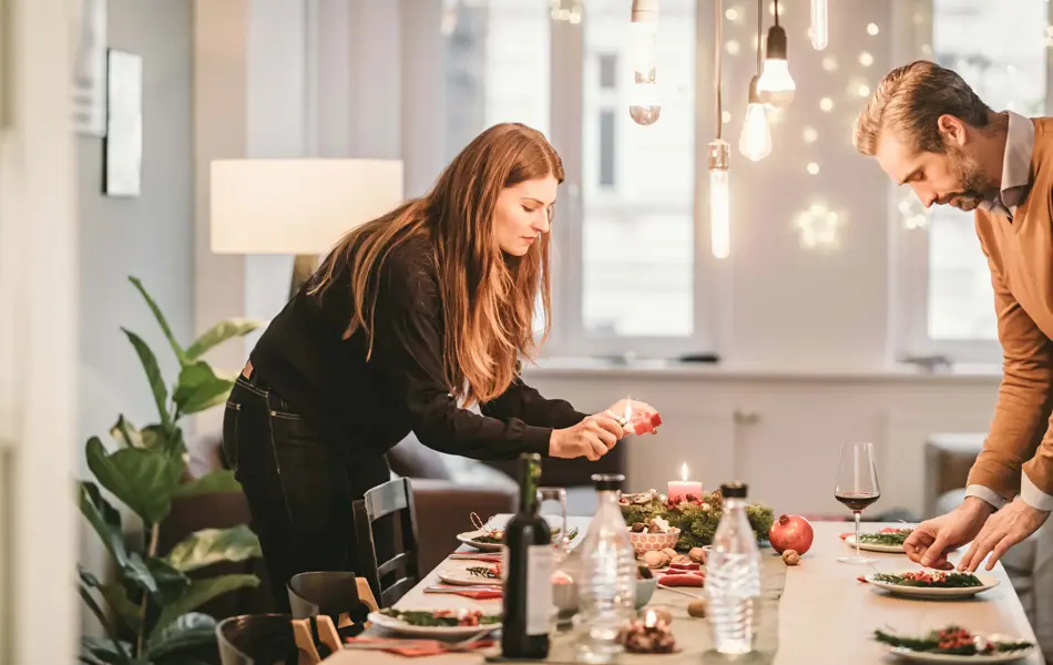 En mann og en dame dekker bordet til julefest