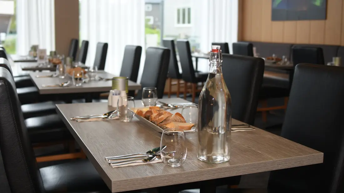 Konferanse og frokostsal, pådekket bord med glass, bestikk og bordpynt