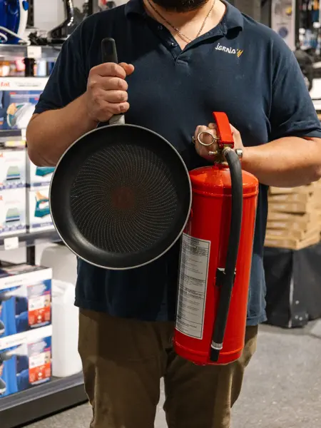 mann holder brukt stekepanne og brannslukkingsapparat