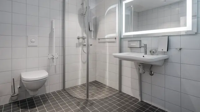Dusj, toalett og vask med god gulvplass og støttearmer rundt toalett på  handikaprom på Thon Hotel Lofoten