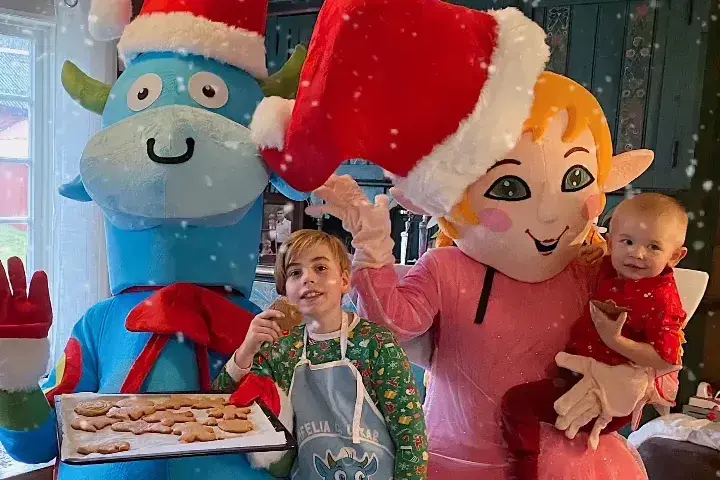 Amfelia og Oskar sammen med to barn, holder opp et brett med pepperkaker