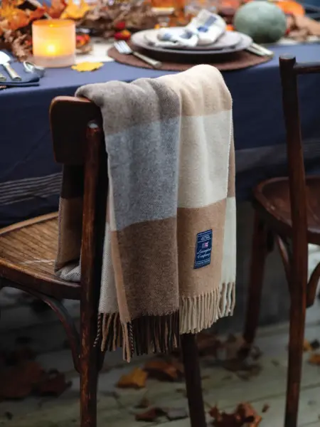 Hagestol dekket med pledd og dekket bord i bakgrunn