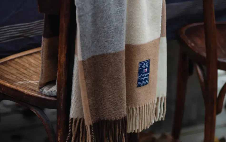 Hagestol dekket med pledd og dekket bord i bakgrunn