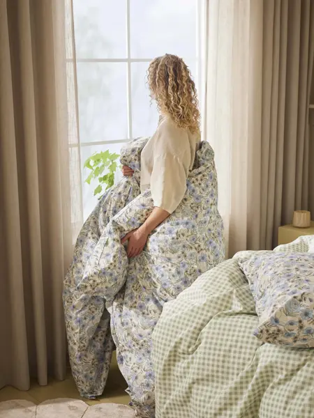 Dame med dyne i blomstermønster rundt seg