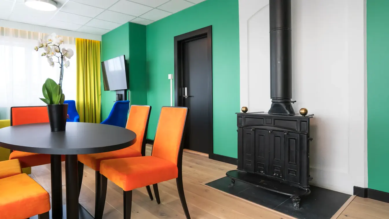 Peis, TV, bord, orange stoler på suite på Thon Hotel Europa i Oslo sentrum rett ved Slottsparken