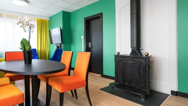 Peis, TV, bord, orange stoler på suite på Thon Hotel Europa i Oslo sentrum rett ved Slottsparken
